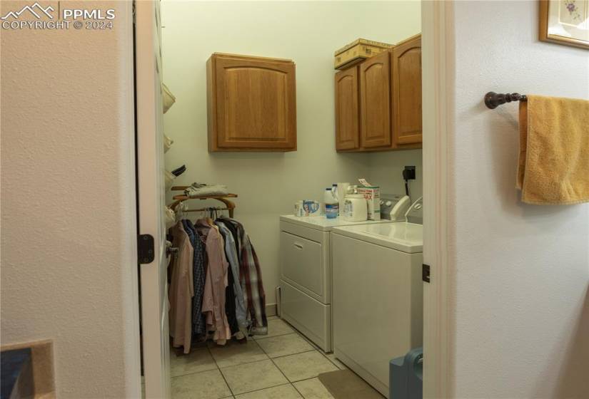 Laundry room with cabinets, washing machine and dryer, and light tile flooring