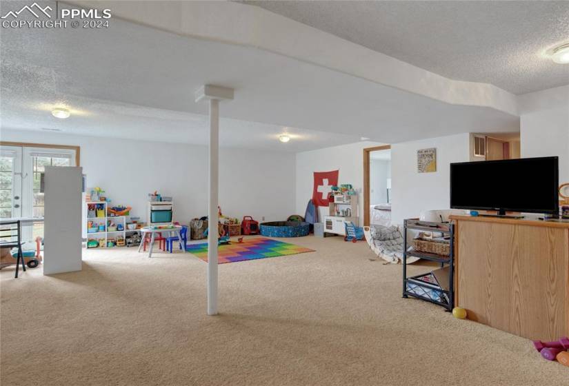 Playroom featuring french doors, carpet, and a textured ceiling