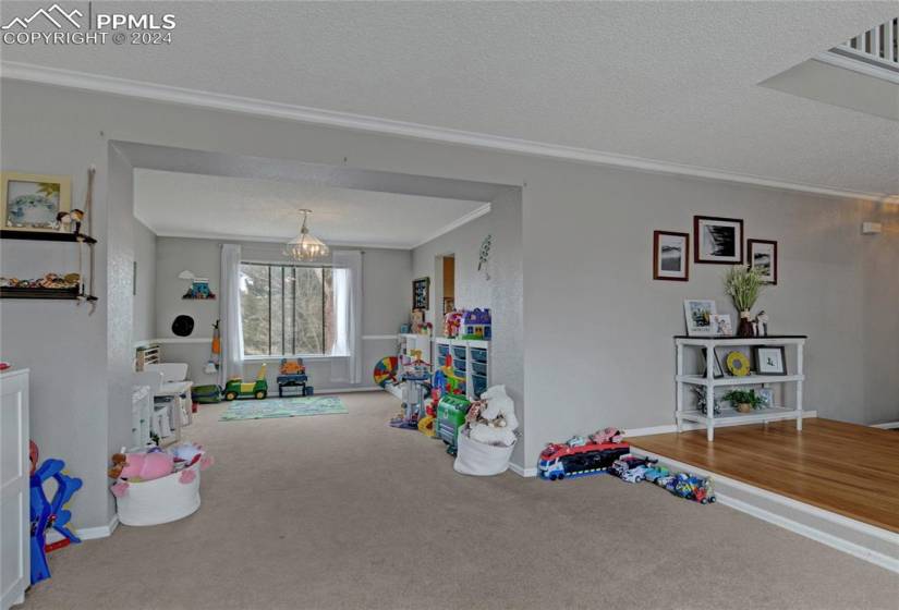 Game room with a textured ceiling, a notable chandelier, carpet, and crown molding