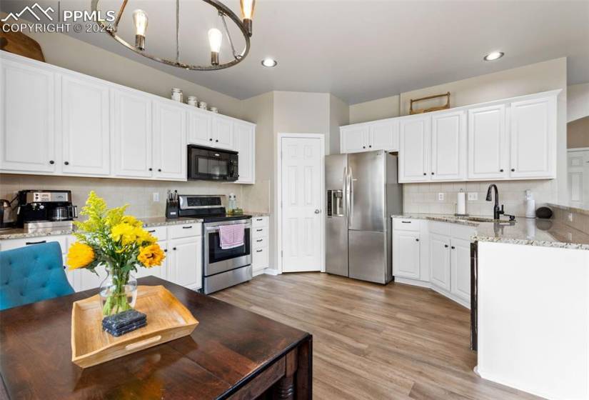 Kitchen featuring light hardwood / wood-style floors, appliances with stainless steel finishes, backsplash, and white cabinetry