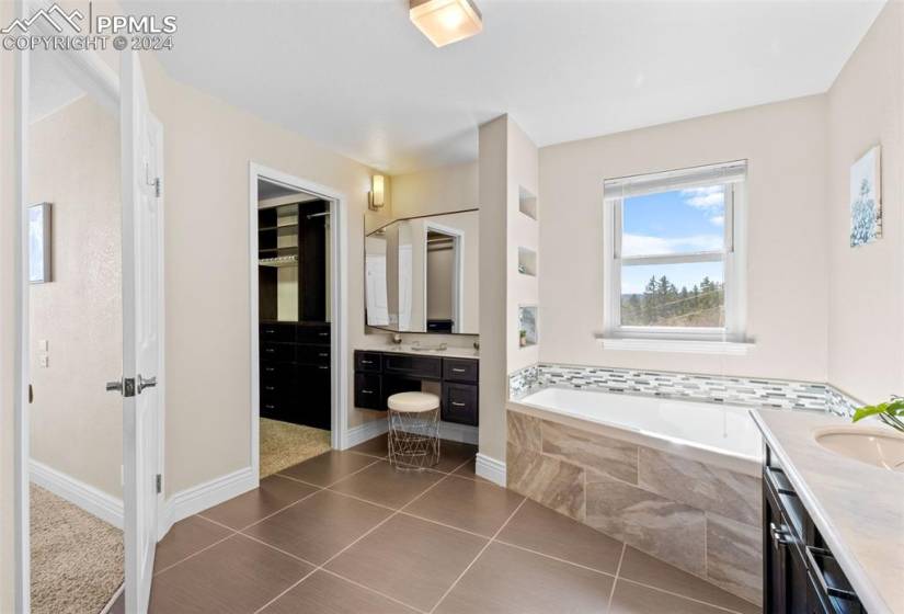 Bathroom with vanity with extensive cabinet space, tile floors, and tiled bath