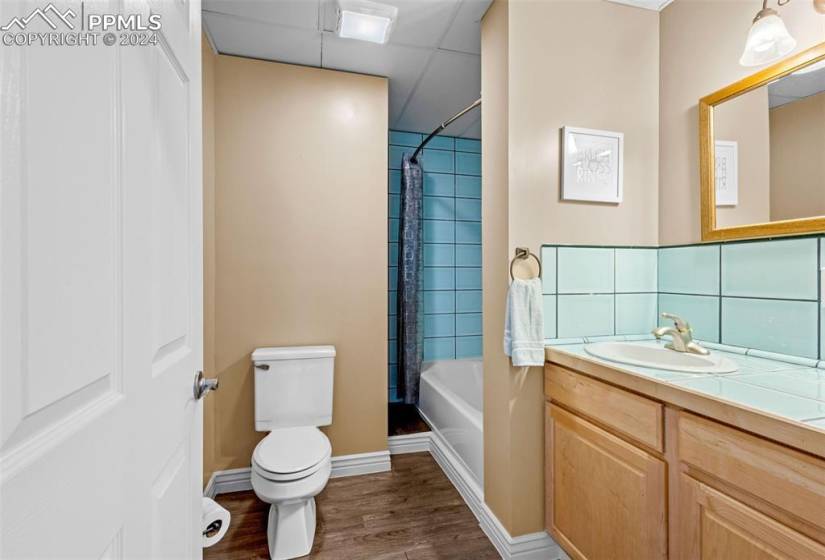 Full bathroom with tiled shower / bath, backsplash, toilet, wood-type flooring, and vanity