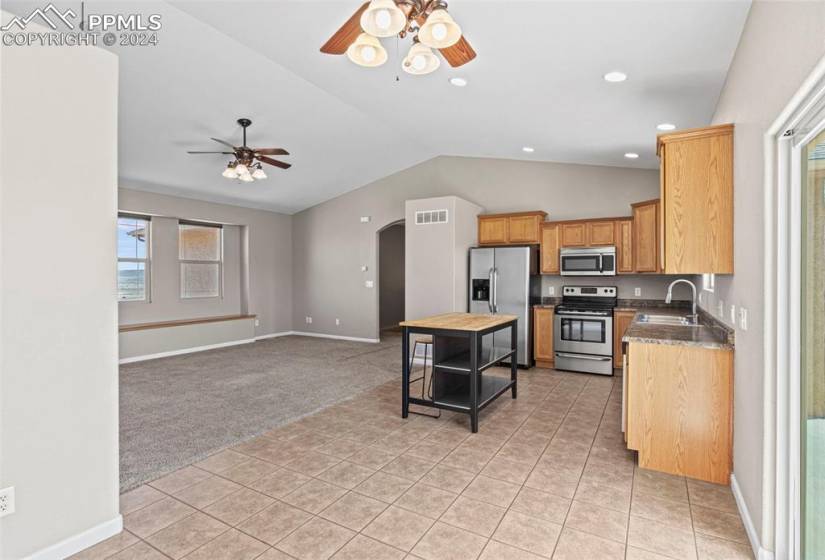 Kitchen featuring vaulted ceiling, stainless steel appliances, ceiling fan, and light tile floors