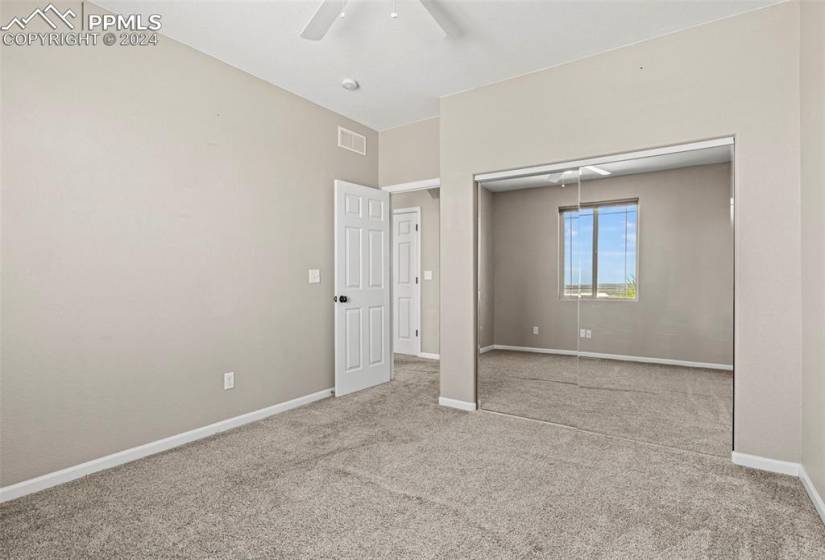 Unfurnished bedroom with light colored carpet, ceiling fan, and a closet