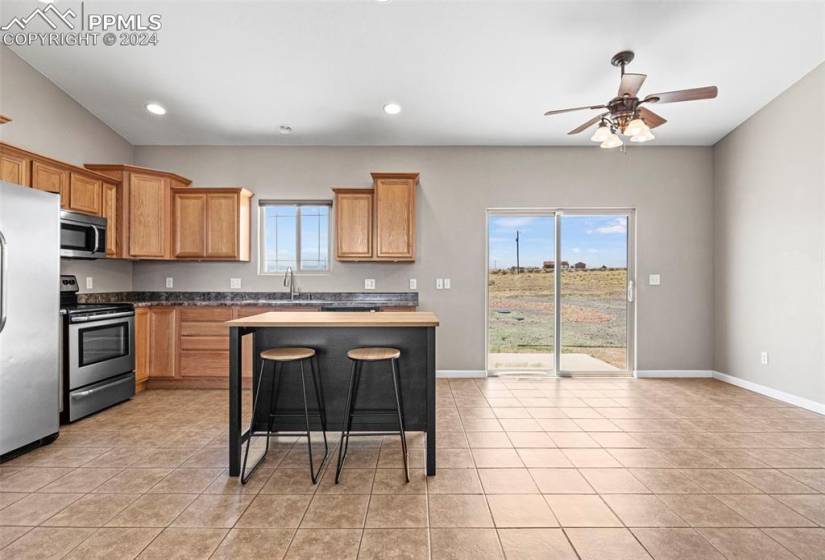 Kitchen with appliances with stainless steel finishes, a breakfast bar area, a wealth of natural light, and light tile floors
