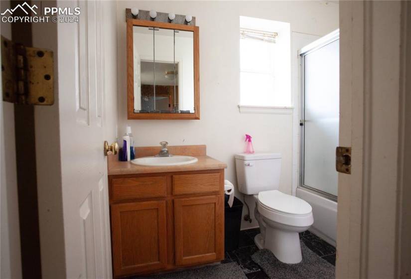 Full bathroom with tile flooring, combined bath / shower with glass door, vanity, and toilet