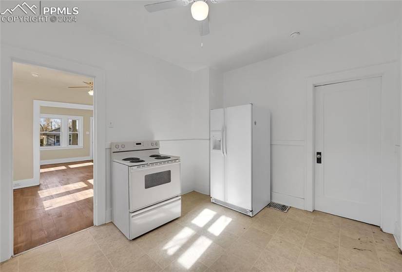 Kitchen featuring white appliances, ceiling fan, and light tile floors