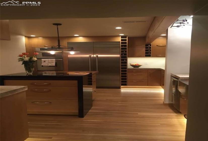 Kitchen featuring light hardwood / wood-style flooring, decorative light fixtures, and appliances with stainless steel finishes