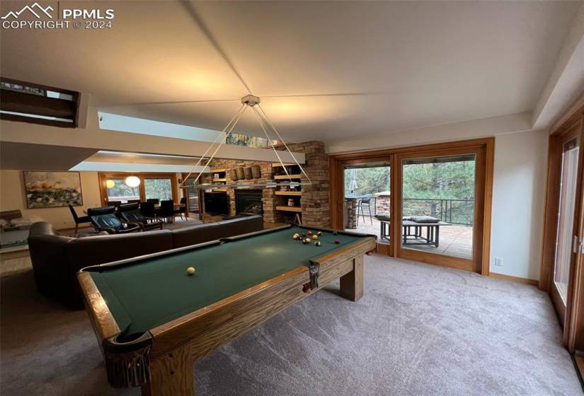 Recreation room with carpet flooring, pool table, and a brick fireplace