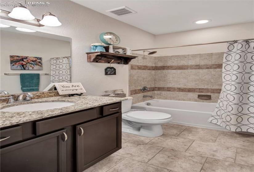 Full bathroom featuring shower / bath combo, toilet, oversized vanity, and tile flooring