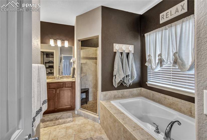 Bathroom featuring tile flooring, vanity, and separate shower and tub