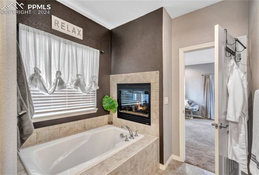 Bathroom with a relaxing tiled bath, tile floors, and a tiled fireplace