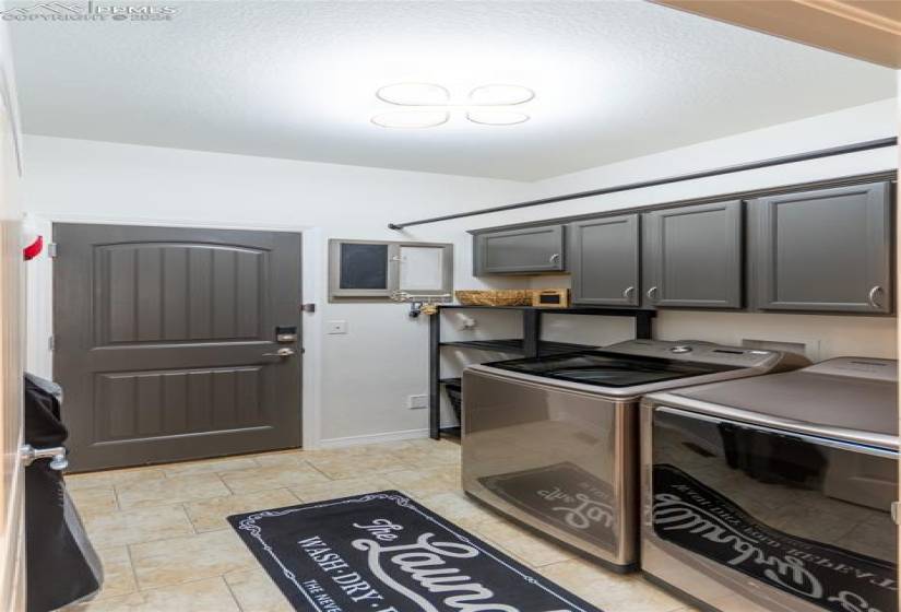 Kitchen with gray cabinetry, light tile floors, and washing machine and clothes dryer
