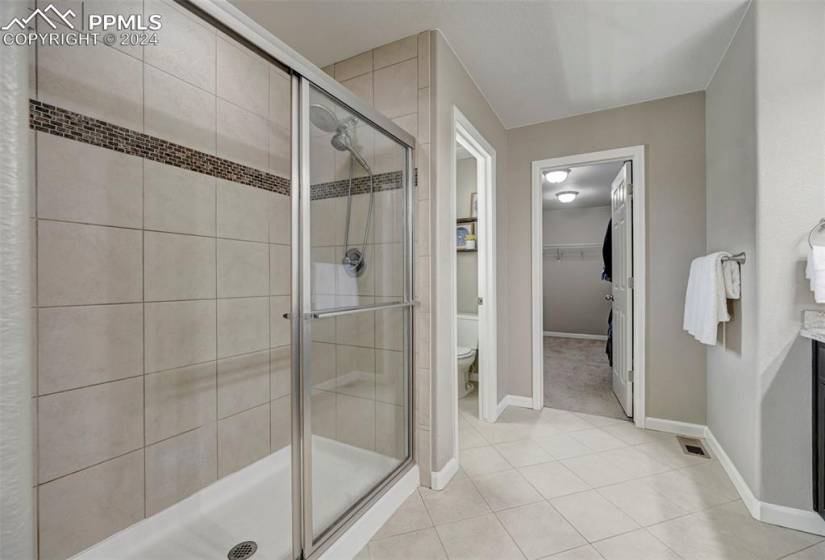 Bathroom with a shower with door, tile flooring, vanity, and toilet