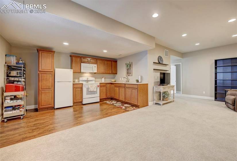 Kitchen with light carpet, white appliances, and sink