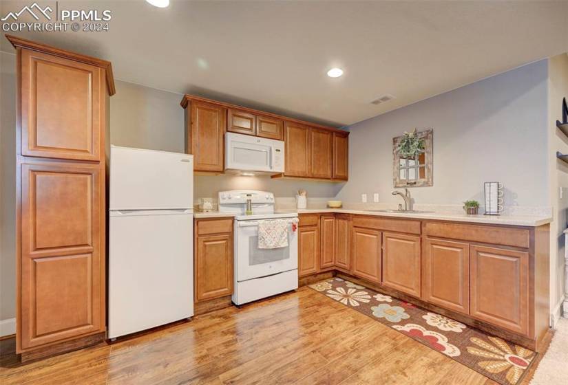 Kitchen featuring light hardwood / wood-style floors, white appliances, and sink
