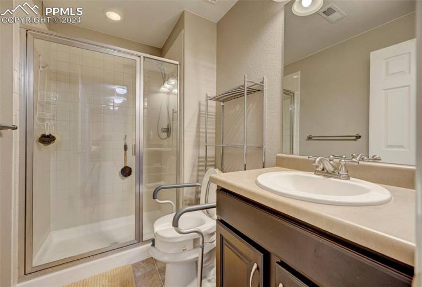 Bathroom with walk in shower, oversized vanity, toilet, and tile flooring