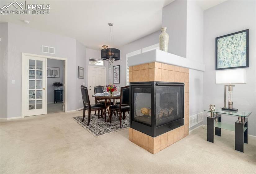 Carpeted dining space featuring a double sided tiled fireplace