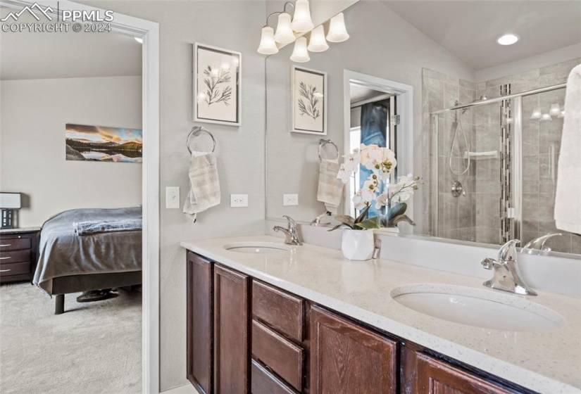 Bathroom featuring dual sinks, an enclosed shower, vaulted ceiling, and large vanity