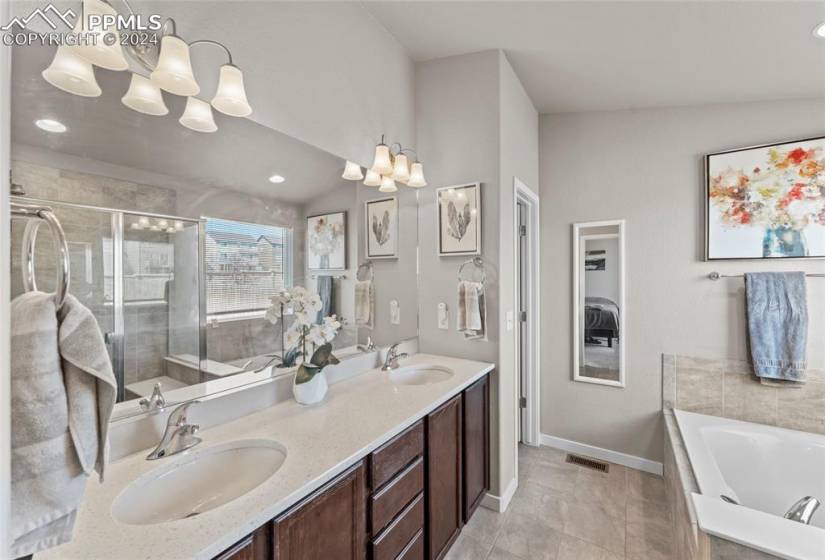 Bathroom featuring lofted ceiling, tile floors, vanity with extensive cabinet space, and dual sinks