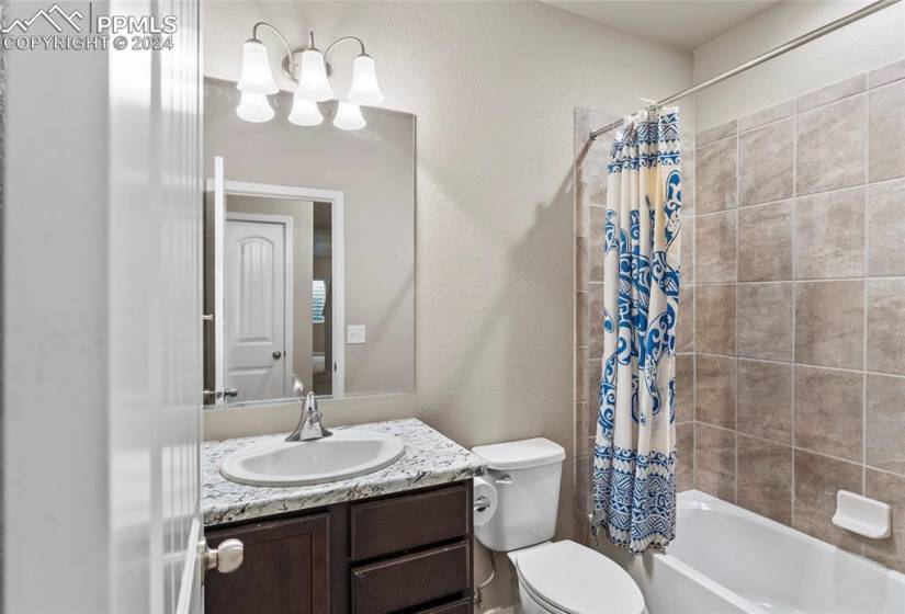 Full bathroom with toilet, shower / bath combo with shower curtain, and large vanity