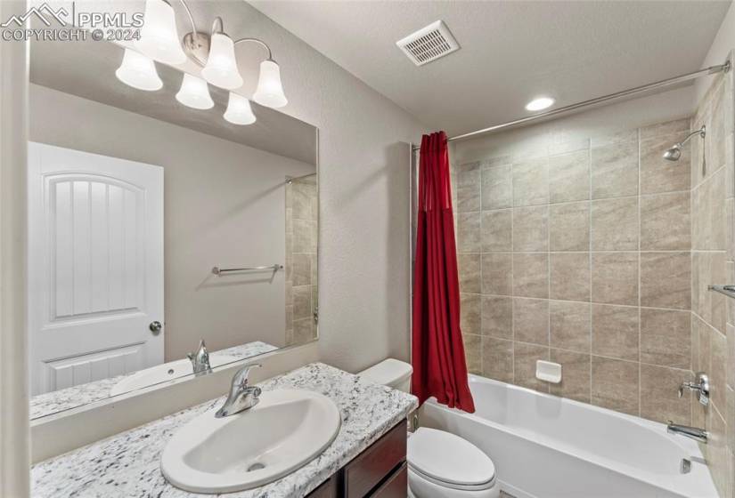 Full bathroom with shower / bath combo, toilet, a textured ceiling, and large vanity