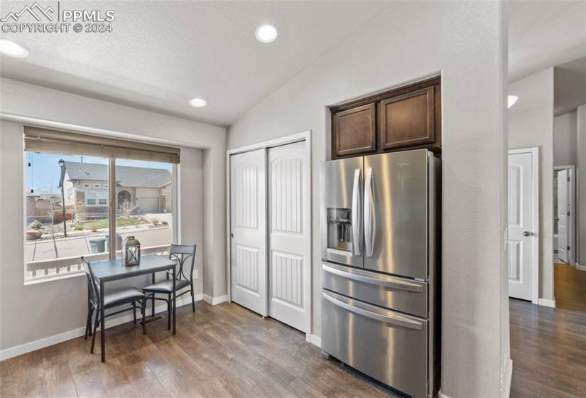 Kitchen featuring stainless steel fridge with ice dispenser, dark brown cabinetry, vaulted ceiling, and dark hardwood / wood-style floors