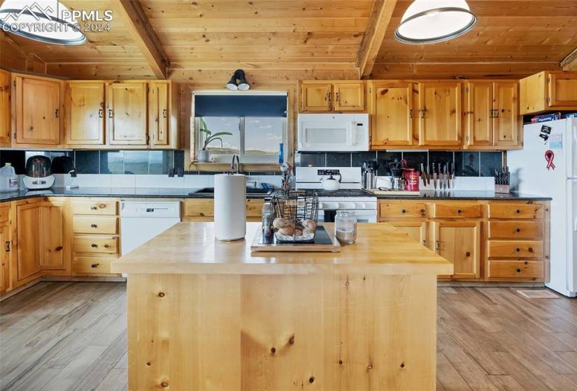 Kitchen with beamed ceiling, white appliances, wood counters, wooden ceiling, and light hardwood / wood-style floors
