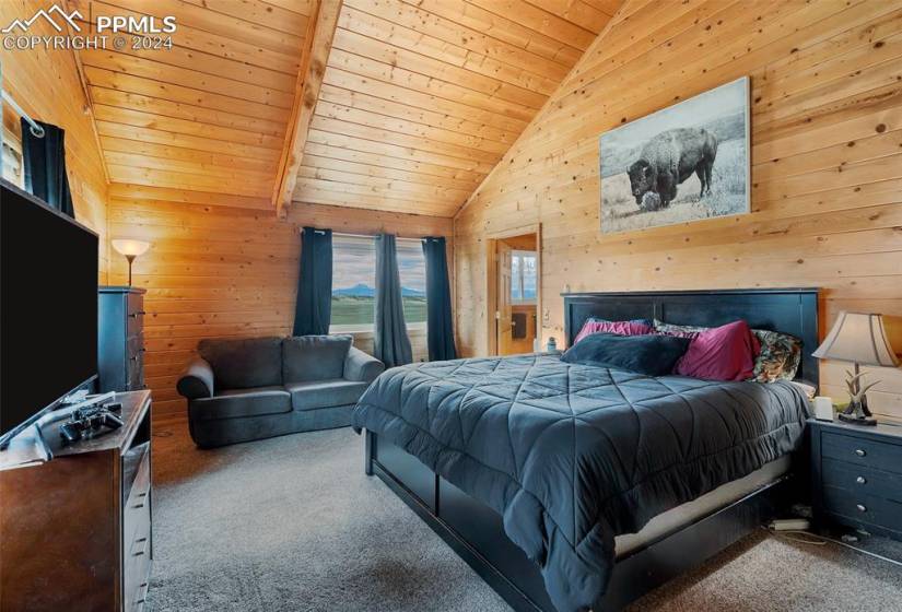 Bedroom featuring light carpet, high vaulted ceiling, beam ceiling, wooden walls, and wooden ceiling