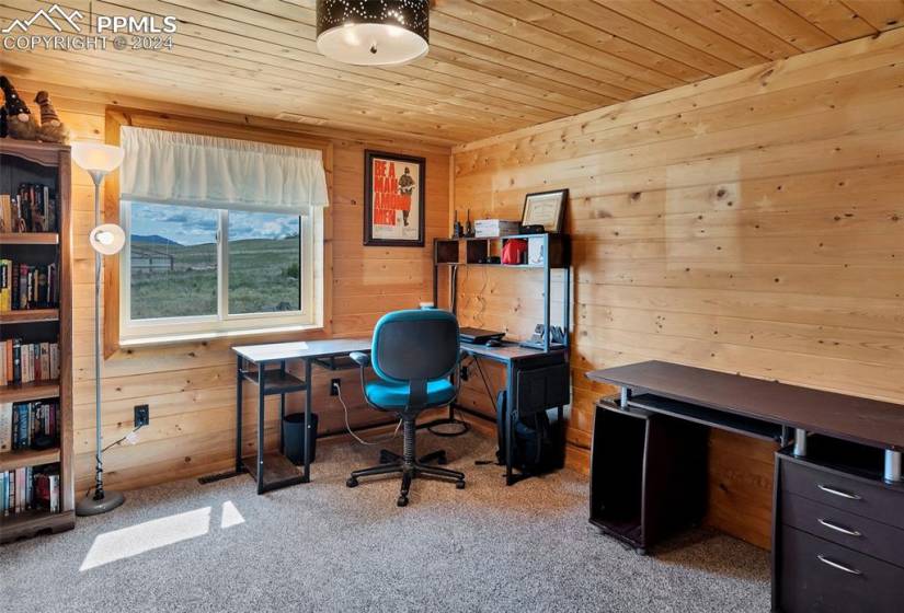 Carpeted home office with wooden ceiling and wooden walls