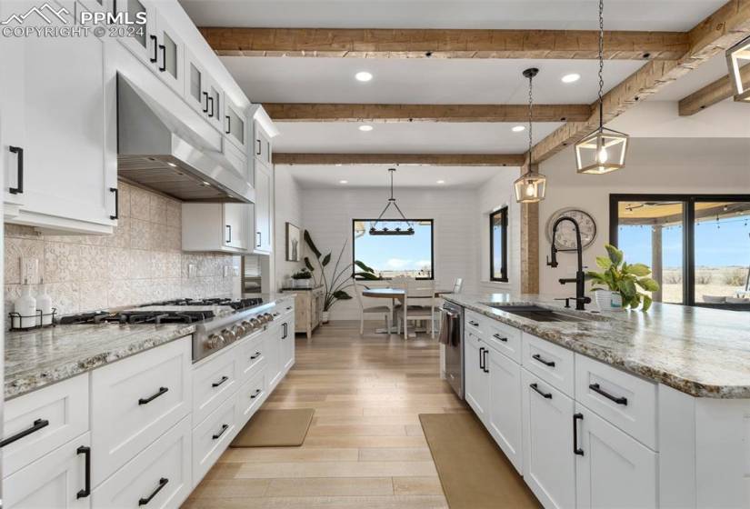Kitchen with wood-style flooring, pendant lighting, and white cabinetry