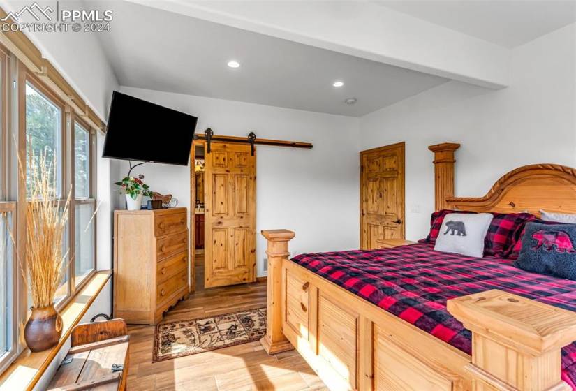 Bedroom with a barn door and light hardwood / wood-style floors