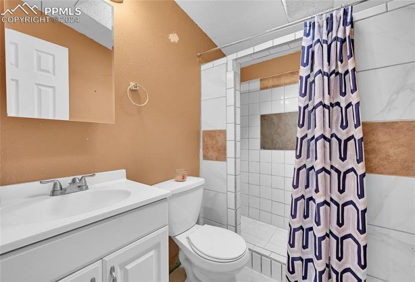 Bathroom with curtained shower, vanity with extensive cabinet space, tile floors, and toilet