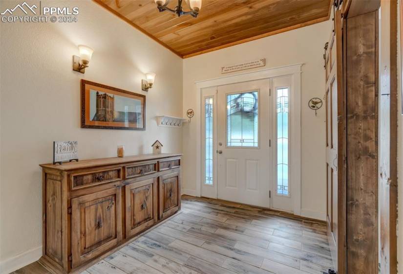 Entrance foyer with wood ceiling, a barn door, and light hardwood / wood-style floors