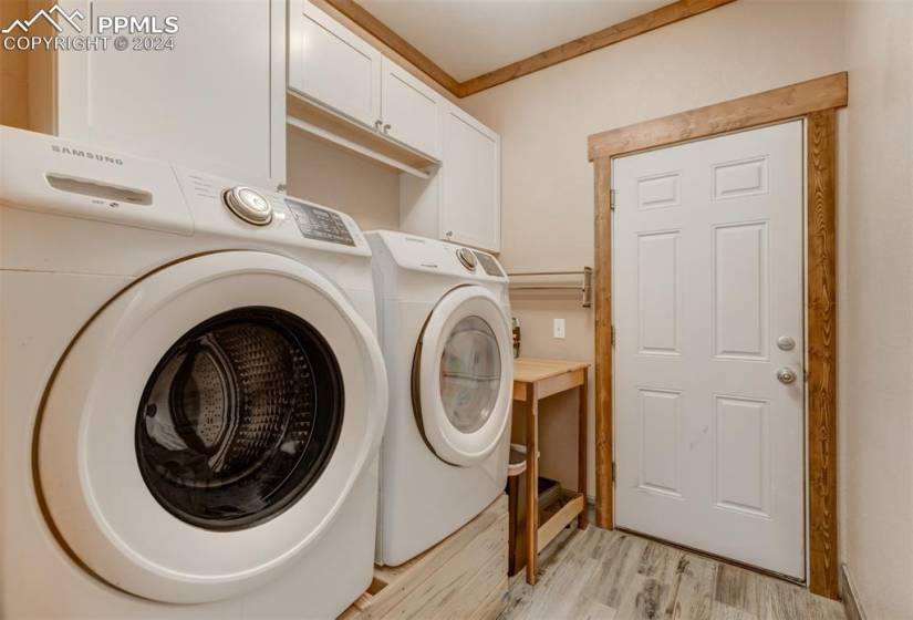 Washroom featuring light hardwood / wood-style flooring, washer and dryer, and cabinets