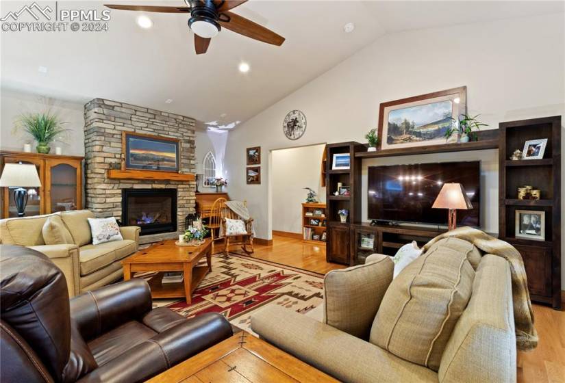 Family room with ceiling fan, gas fireplace, vaulted ceiling, and hardwood flooring