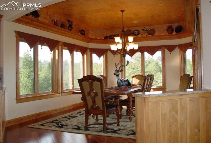 Dining area with a raised ceiling, a chandelier, and hardwood / wood-style floors