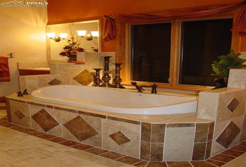 Bathroom featuring a chandelier, tiled bath, and tile floors