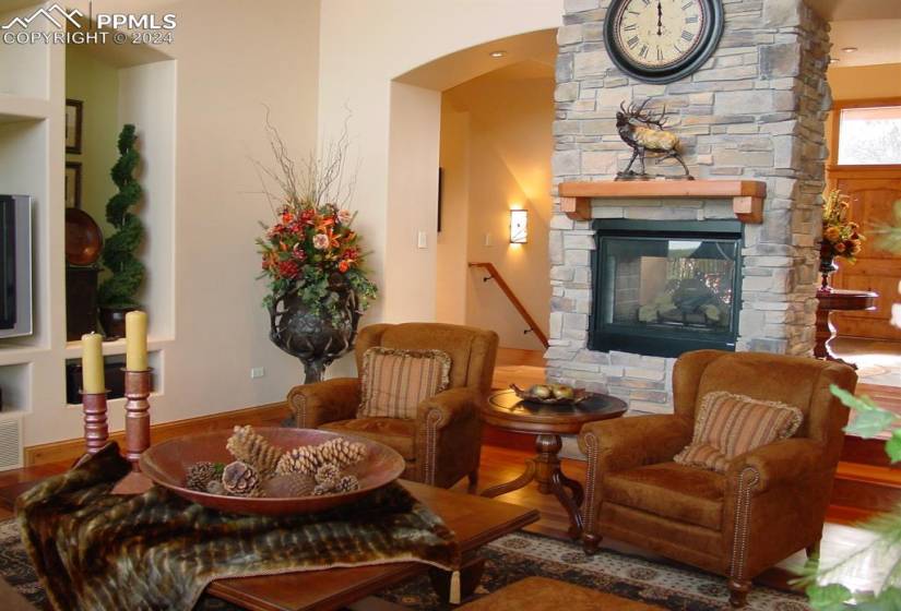 Sitting room featuring hardwood / wood-style flooring, a stone fireplace, and built in features
