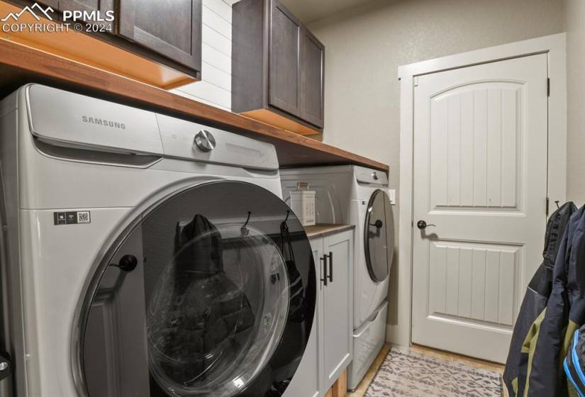 Laundry area featuring cabinets, light tile floors, and washing machine and clothes dryer