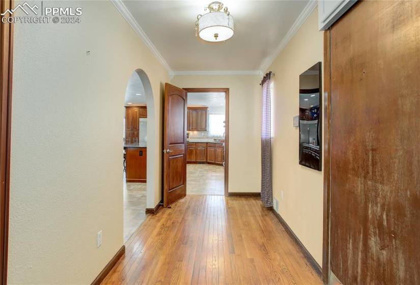 Hallway with light hardwood / wood-style floors and crown molding