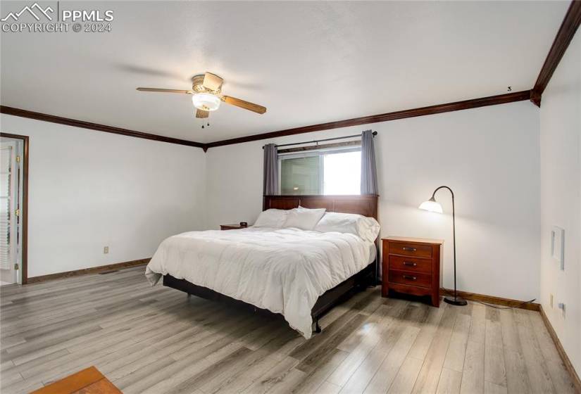 Bedroom with ceiling fan, crown molding, and hardwood / wood-style flooring