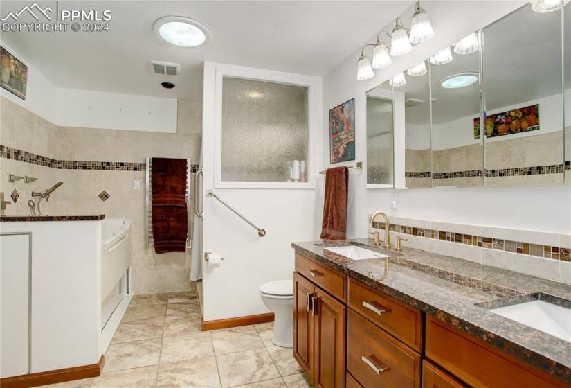 Bathroom featuring dual bowl vanity, tile floors, tile walls, tasteful backsplash, and toilet