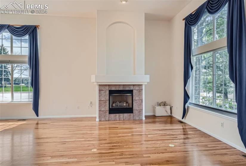 Unfurnished living room with a healthy amount of sunlight, a tiled fireplace, and light hardwood / wood-style floors