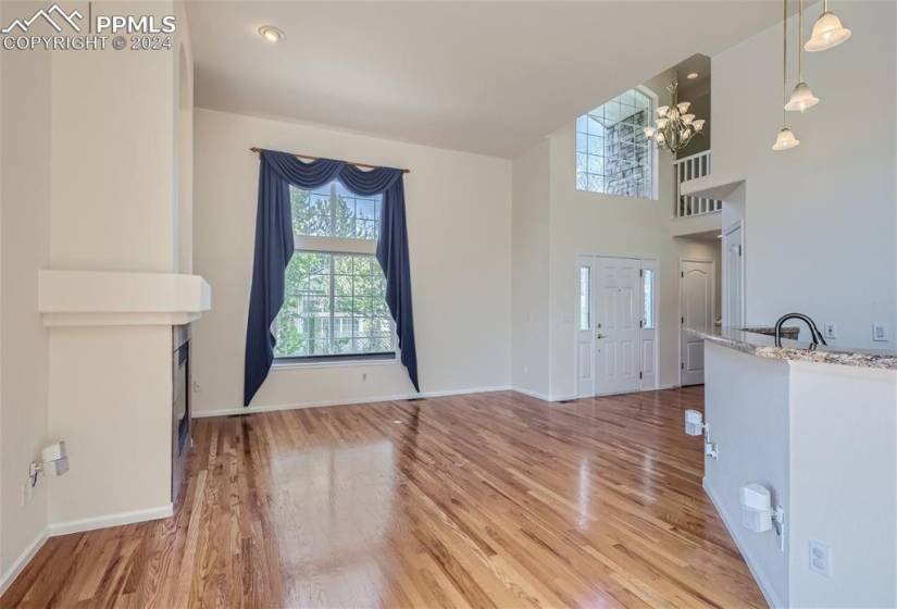 Spare room with sink, a high ceiling, light wood-type flooring, and an inviting chandelier