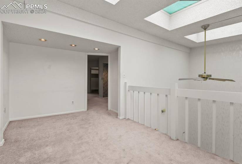 Carpeted empty room with a skylight, ceiling fan, and a textured ceiling