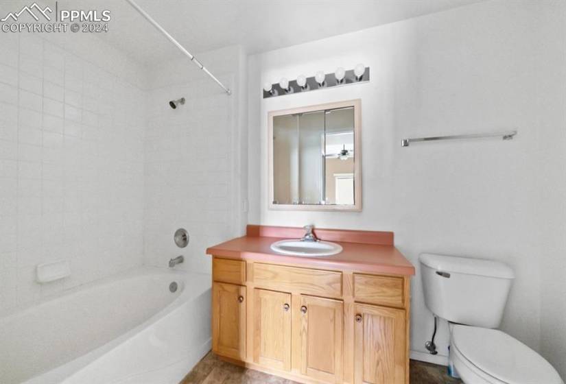 Full bathroom featuring hardwood / wood-style floors, tiled shower / bath, vanity, and toilet
