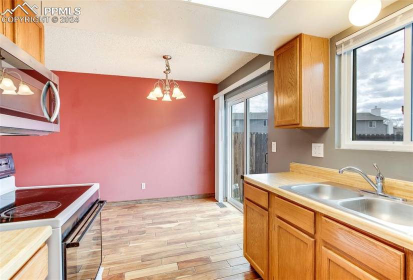 Kitchen featuring hanging light fixtures, light wood-type flooring, a chandelier, sink, and white electric range