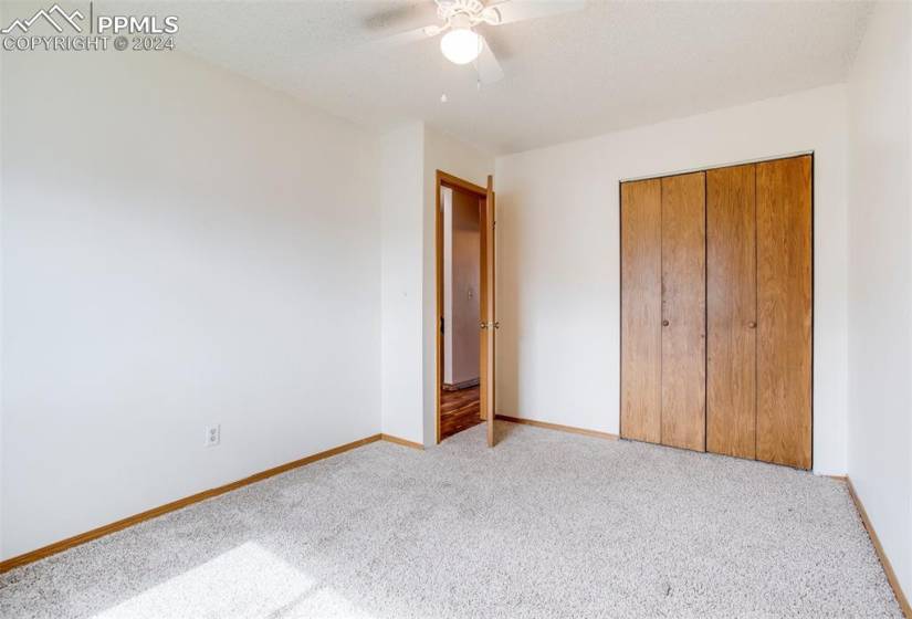 Unfurnished bedroom with a closet, ceiling fan, and carpet floors