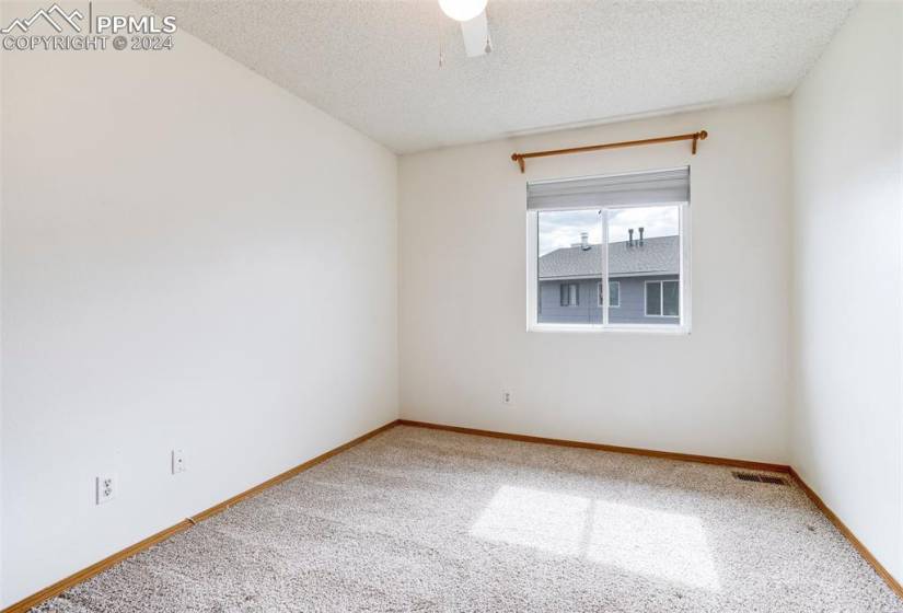 Unfurnished room featuring a textured ceiling, ceiling fan, and carpet